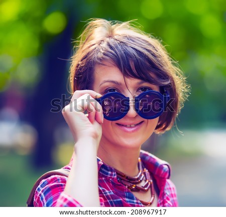 portrait of a pretty woman in sunglasses on background of city park, age forty to forty-five years