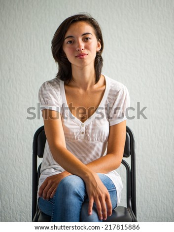 Chinese woman sitting on a chair on a background of bright wall