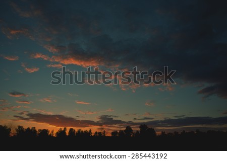 blurred background landscape in the countryside of woods and clouds at sunset