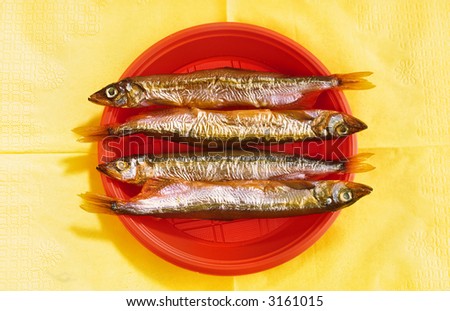 Smoked fish in  red disposable plate on  yellow background
