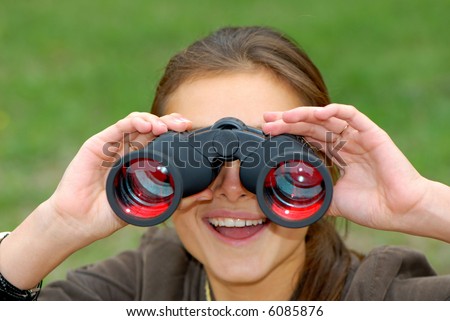 woman looks in the field-glass on  green background in park