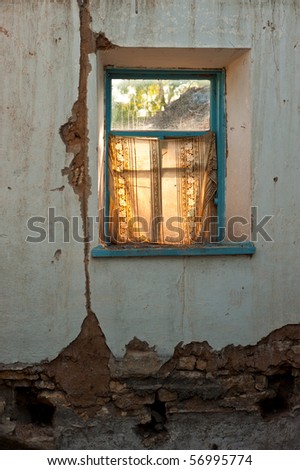 old window with bits and pieces of wall of the destroyed house, lighted up by daylight