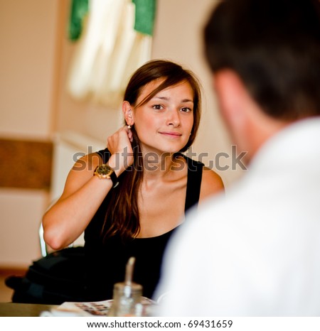 beautiful young woman speaks with the man in cafe and does up hair