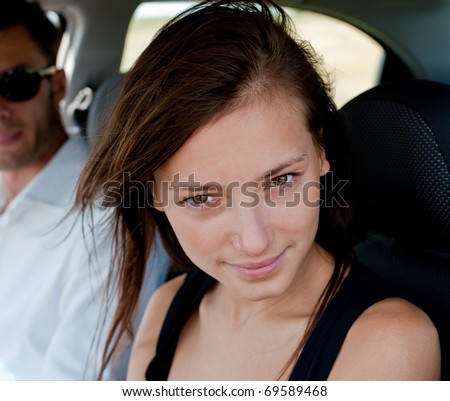 Portrait of the young beautiful woman against the young man in the car