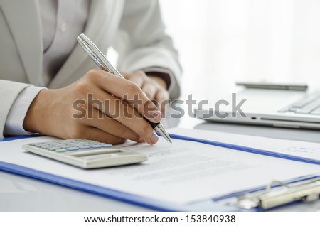 Businesswoman writing down on the document