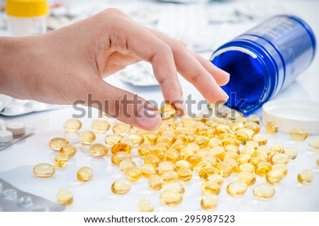 womanâ??s hand holding a fish oil pill