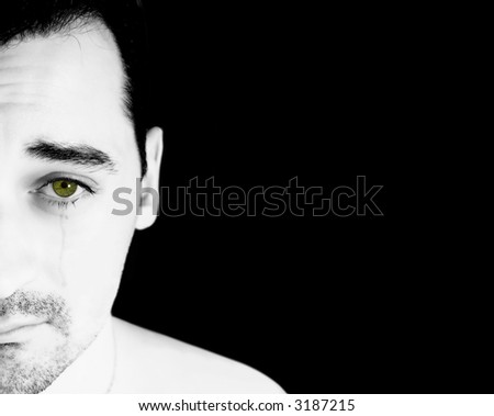 A white man with green eye crying isolated on a black background