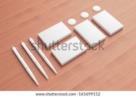 Blank Stationery / Corporate ID Set on wooden background. Consist of Business cards, pens and buttons.
