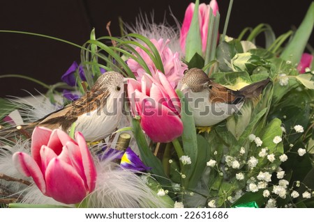 Photo of fragment of rich and beautiful bouquet of different flowers with two small toy birds