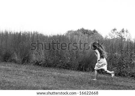 Girl running through fields, black and white image, intentional grain added