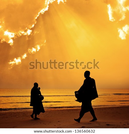 Silhouette of monk walk on the beach with beutuful , Huahin , Thailand