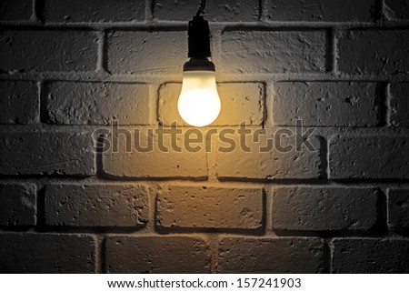 Light bulb turn on in room with brick wall