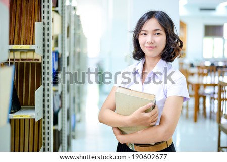 A portrait of an Asian college student in uniform studying in the library , thai student