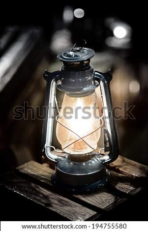 Vintage fashioned rustic kerosene oil lantern lamp burning with a soft glow light in an antique country barn