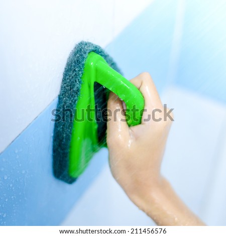 Hand cleaning wet ceramic wall in toilet