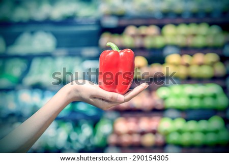 Woman hand holding red sweet pepper in supermarket