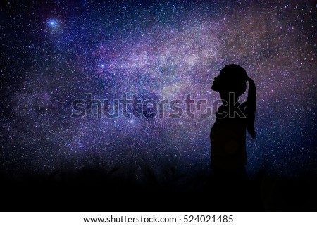 Silhouette of woman stand alone in the night with detail from the milky way and  stars field background