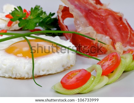 Fried Eggs Sunny Side Up with Bacon, Lettuce and vegetables closeup on gray plate