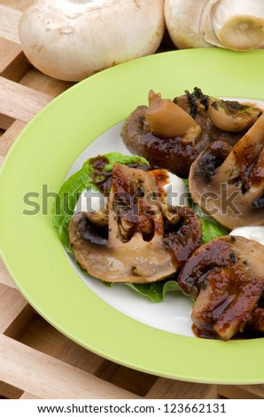 Cooked Mushrooms with Grill Sauce, Sour Cream and Greens on Plate closeup on Wood background and Raw Mushrooms