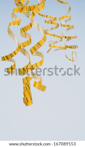 Arrangement of Five Striped Yellow Curly Streamers Hanging Down isolated on Blue background