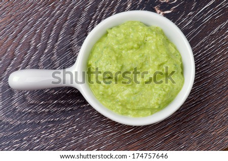 Wasabi Sauce in White Gravy Boat isolated on Wooden background. Top View