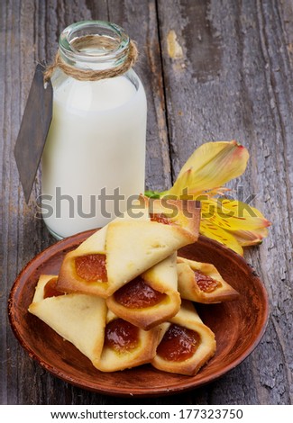 Homemade Pastry Jam Wrapped and Bottle of Milk Decorated with Yellow Flower isolated on Rustic Wooden background