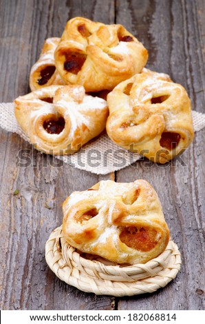 Arrangement of Homemade Pastry Baskets Jam Wrapped with Sugar Powder on Wicker Napkin and Plate closeup on Rustic Wooden background.