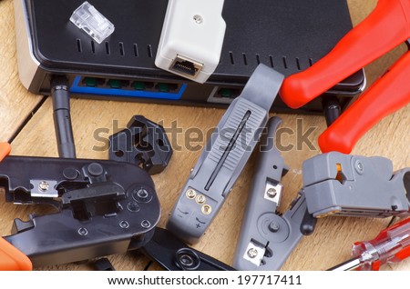 Arrangement of Computer Network Tools for Crimping, Cutting and Connecting with Router closeup on Wooden background