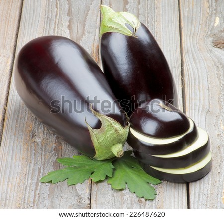 Stack of Ripe Raw Eggplants Full Body and Slices with Leafs isolated on Rustic Wooden background