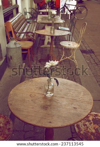 Empty Sidewalk Cafe with Wooden Tables and Old Chairs on Cobblestone Street in Copenhagen Outdoors
