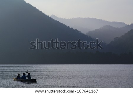 A boat is paddled towards over calm water. They leave a small wake as their boat cuts through the water.