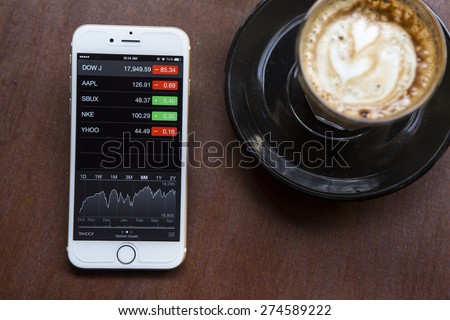 CHIANG MAI, THAILAND - APRIL 22, 2015: iPhone 6 with application Stocks of Apple on the screen in coffee shop cafe. iPhone 6 was created and developed by the Apple inc.