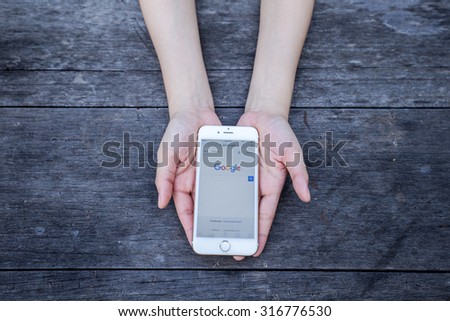 CHIANG RAI, THAILAND - SEPTEMBER 13, 2015: Woman holding Apple iphone show Google search engine on smartphone device screen background.