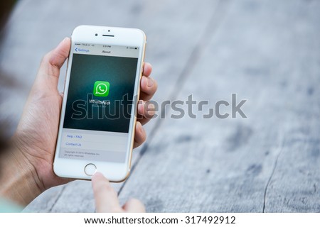 CHIANG RAI, THAILAND - SEPTEMBER 13, 2015: Woman try to use social Internet service WhatsApp screen on blue background. iPhone 6 was created and developed by the Apple inc.