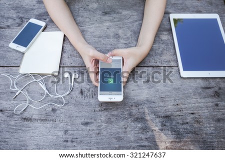 CHIANG RAI, THAILAND - SEPTEMBER 13, 2015: Woman try to use social Internet service WhatsApp screen on blue background. iPhone 6 was created and developed by the Apple inc.