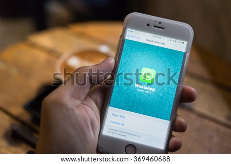 CHIANG MAI, THAILAND - JANUARY 25, 2016: Man try to use social Internet service WhatsApp screen on blue background. iPhone 6S was created and developed by the Apple inc.