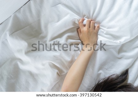 Hand sign orgasm of woman on white bed in hotel