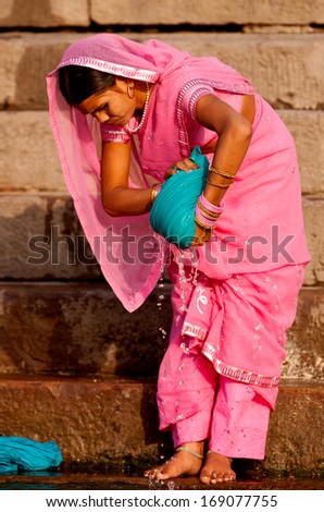 VARANASI, INDIA - APRIL 24: Unidentified hindu woman washing her clothes before taking bath in the river Ganga on April 24, 2011 in Varanasi, India. The holy ritual bath is held every day.