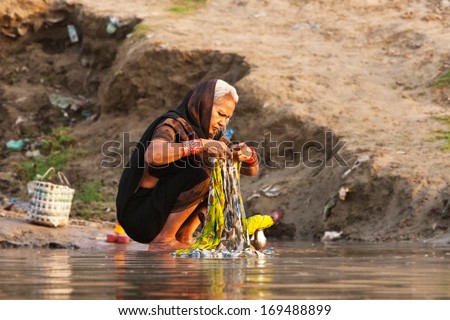 VARANASI, INDIA - APRIL 24: Unidentified woman washes her clothes in the river Ganga on April 24, 2011 in the holy city of Varanasi, India. The holy ritual of washing and bathing is held every day.