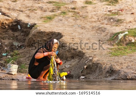 VARANASI, INDIA - APRIL 24: Unidentified woman washes her clothes in the river Ganga on April 24, 2011 in the holy city of Varanasi, India. The holy ritual of washing and bathing is held every day.