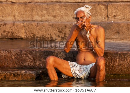 VARANASI, INDIA - APRIL 24: Unidentified man taking ritual bath in the river Ganga on April 24, 2011 in the holy city of Varanasi, India. The holy ritual of washing and bathing is held every day.