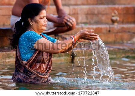 VARANASI, INDIA - APRIL 23: Unidentified woman taking ritual bath in the river Ganga on April 23, 2011 in the holy city of Varanasi, India. The holy ritual of washing and bathing is held every day.