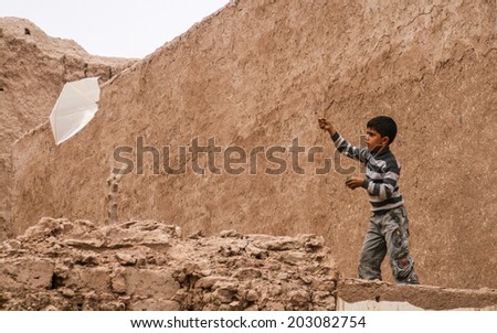 HERAT, AFGHANISTAN - OCT 24: Unidentified Afghan boy playing with his kite on October 24, 2012 in Herat, Afghanistan. Herat is the third largest city of Afghanistan, with a population of about 450,000