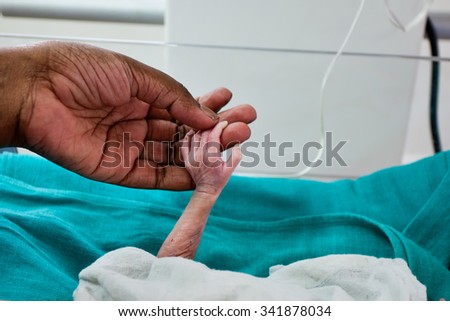 RAXAUL, INDIA - OCT 21: Hands of an Indian woman and her newborn baby\
 in a local hospital on Oct 21, 2011 in Raxaul, Bihar, India. Bihar is one of the poorest states in India.