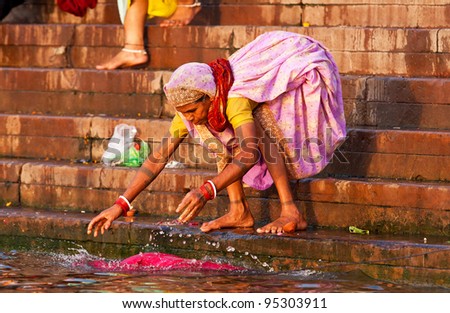 VARANASI, INDIA - APRIL 23: Unidentified woman washes her clothes in the river Ganga on April 23, 2011 in the holy city of Varanasi, India. The holy ritual of washing is held every day.