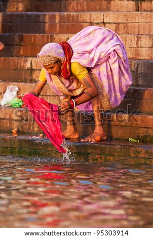 VARANASI, INDIA - APRIL 23: Unidentified woman washes her clothes in the river Ganga on April 23, 2011 in the holy city of Varanasi, India. The holy ritual of washing is held every day.