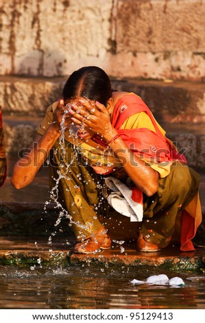 VARANASI, INDIA - APRIL 23: Unidentified woman washes her face in the river Ganga on April 23, 2011 in the holy city of Varanasi, India. The holy ritual of washing is held every day.