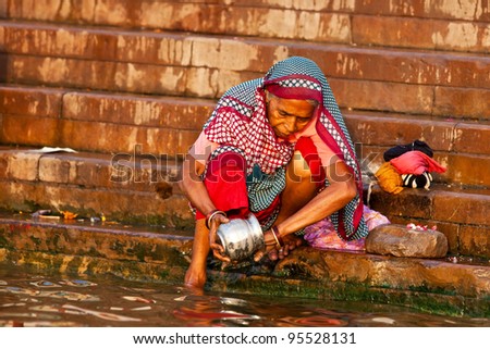 VARANASI, INDIA - APRIL 23: Unidentified woman washing her cup in the river Ganga on April 23, 2011 in the holy city of Varanasi, India. The holy ritual of washing is held every day.