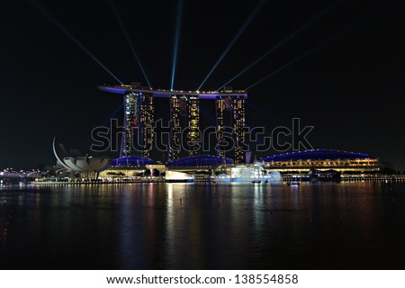 SINGAPORE - MAY 14: The 8 billion dollar Marina Bay Sands resort and casino illuminated at night by a laser show on May 14, 2013 in Singapore.