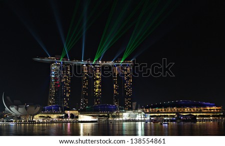 SINGAPORE - MAY 14: The 8 billion dollar Marina Bay Sands resort and casino illuminated at night by a laser show on May 14, 2013 in Singapore.
